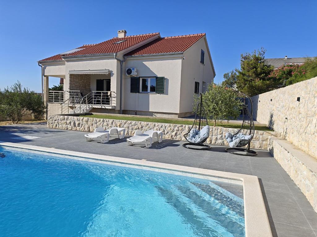 a villa with a swimming pool in front of a house at Villa Pauliana in Povljana