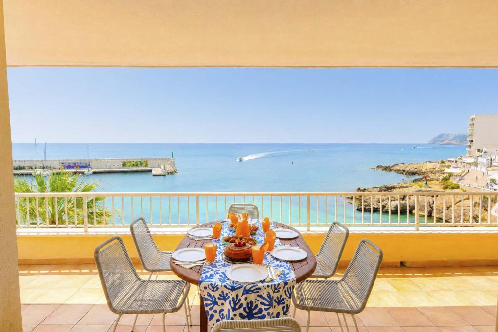 a table on a balcony with a view of the ocean at Seafront Cala Ratjada Apartment in Cala Ratjada