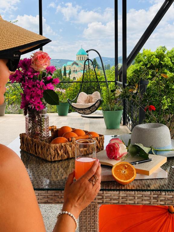 a woman sitting at a table with a glass of juice at Hotel Orange Kutaisi in Kutaisi