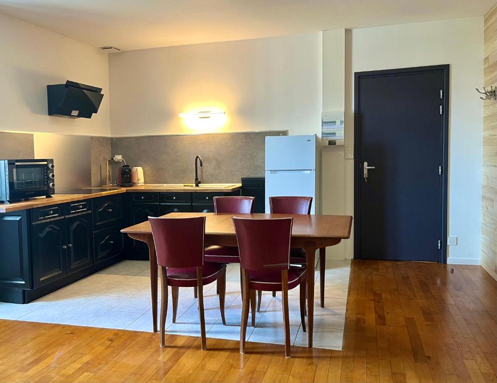 a kitchen with a wooden table and chairs and a kitchen with black cabinets at Emmanon - Appartement in La Coquille