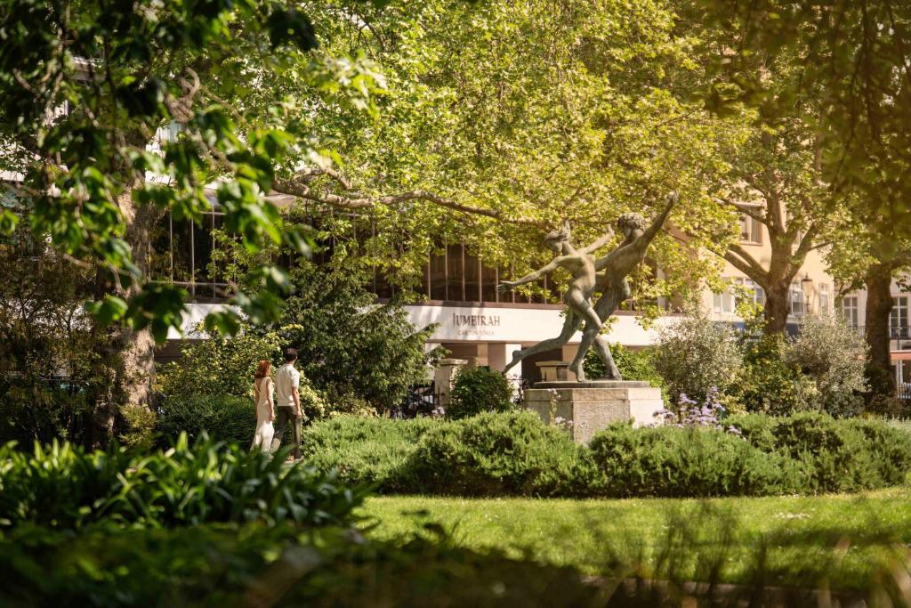 two people standing in a park with a statue at Jumeirah Carlton Tower London in London