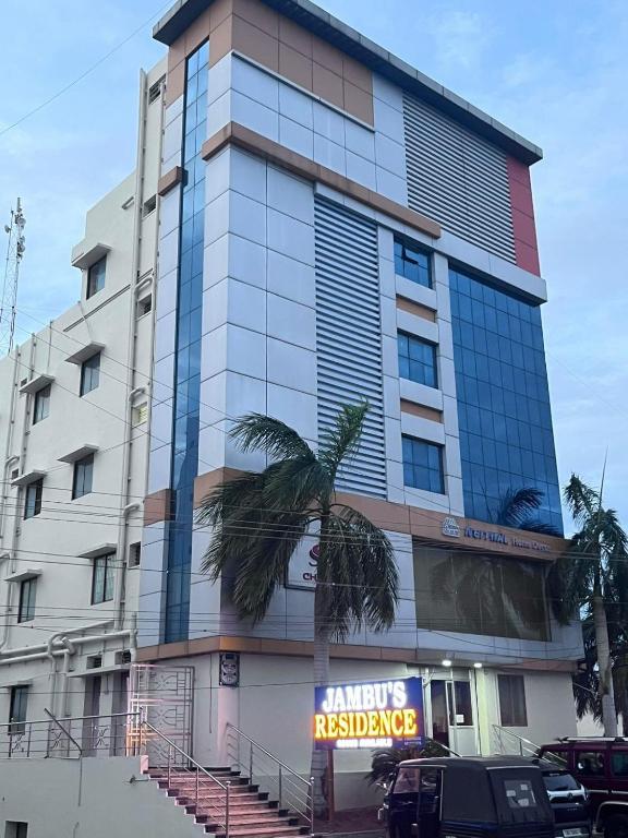 a tall building with a palm tree in front of it at jambu's residence in Karūr