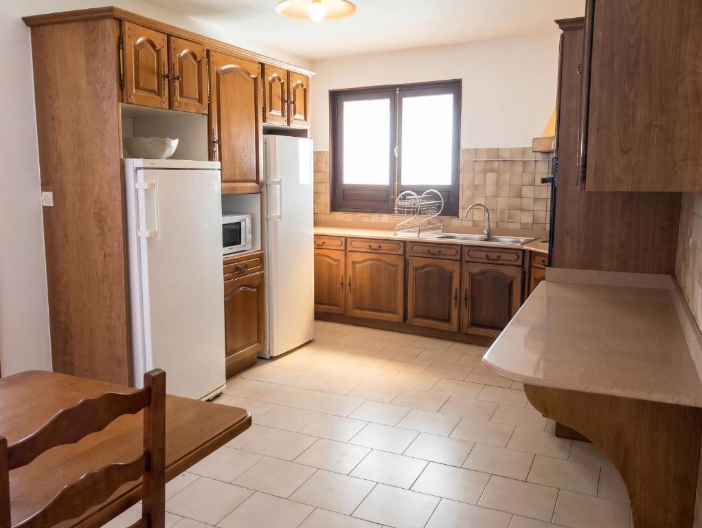 a kitchen with wooden cabinets and a white refrigerator at Appartement lumineux aux Trois-Îlets in Les Trois-Îlets