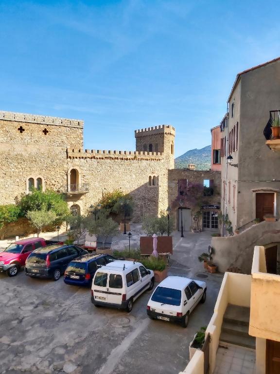 a group of cars parked in a parking lot in front of a castle at Appartement spacieux à Algajola in Algajola