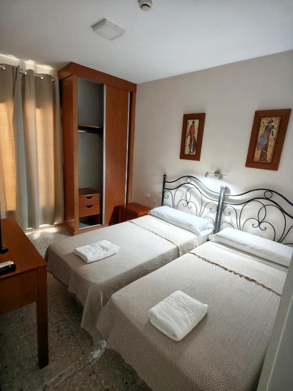 a bedroom with two beds and a table at H Arkanta in Arganda del Rey