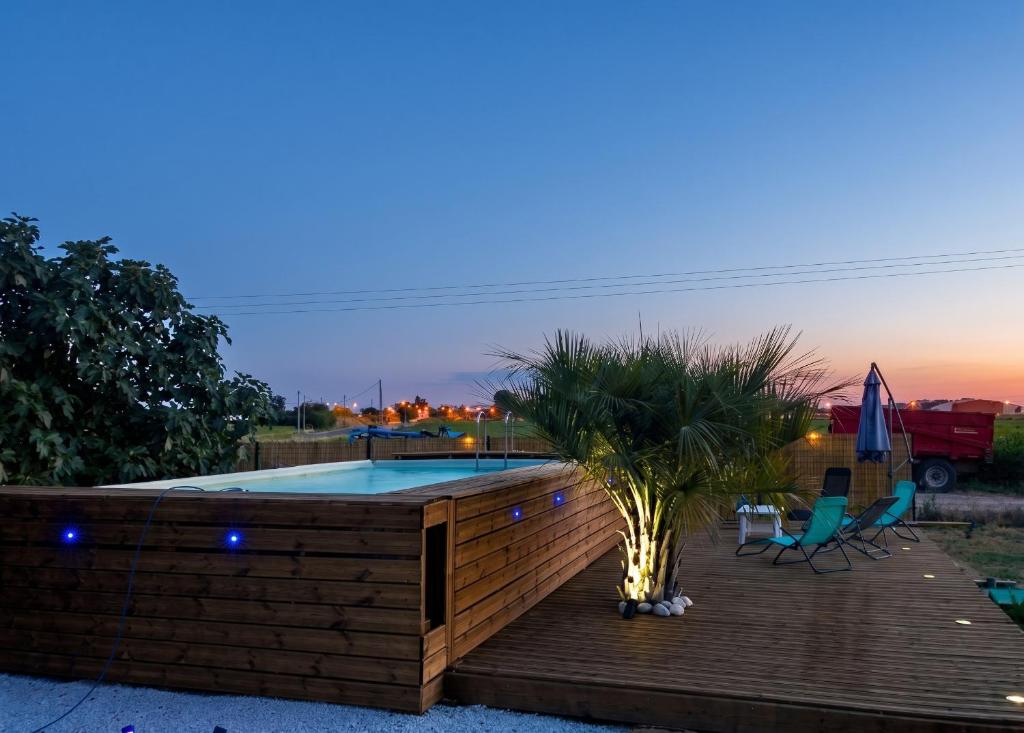 a deck with a pool and a palm tree at Studio charmant à Saint-Jory, 25 m², piscine partagée in Saint-Jory