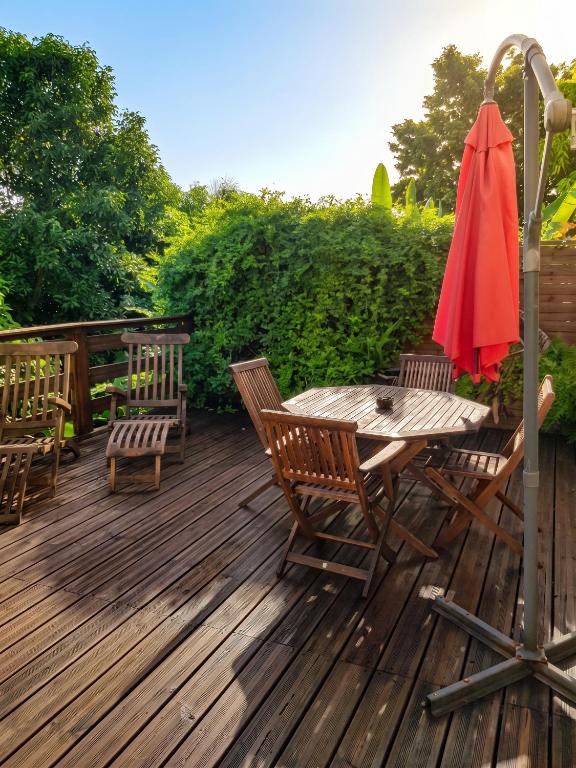 a wooden deck with a table and chairs and an umbrella at Appartement Privilégié Le Moule 70 m² + Piscine in Le Moule