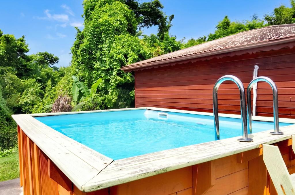 a swimming pool with a wooden deck and metal faucets at Bungalow charmant au Gosier in Le Gosier