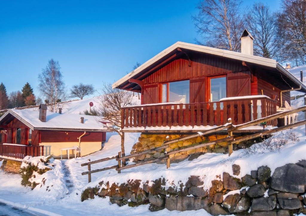 a log cabin in the snow with a porch at Chalet charmant au Tholy avec piscine partagée in Le Tholy