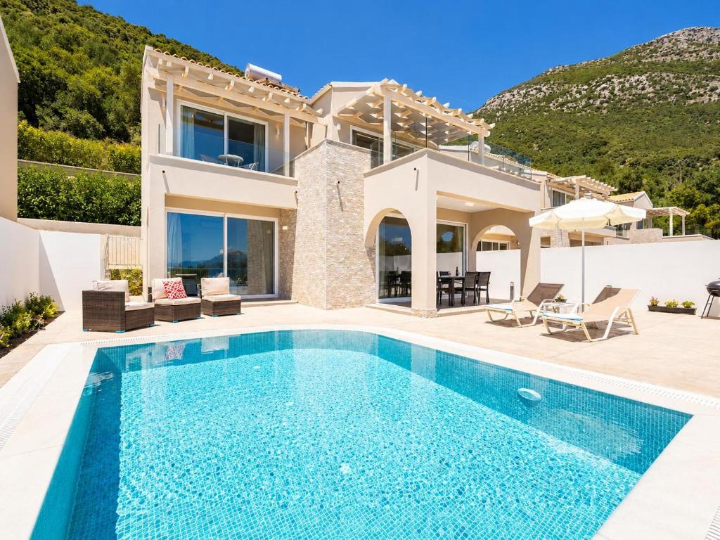 a villa with a swimming pool in front of a house at Villa Alora in Barbati