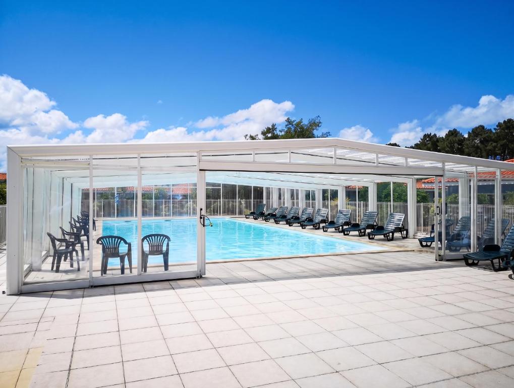 a pavilion with a swimming pool with chairs and a pool at Maison confortable à Parentis-en-Born avec piscine partagée in Parentis-en-Born