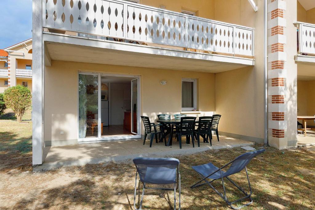 a patio with a table and chairs and a balcony at Appartement chez Coco avec piscine in Soulac-sur-Mer