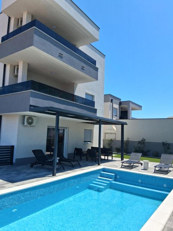 a swimming pool in front of a house at Mima apartments in Povljana