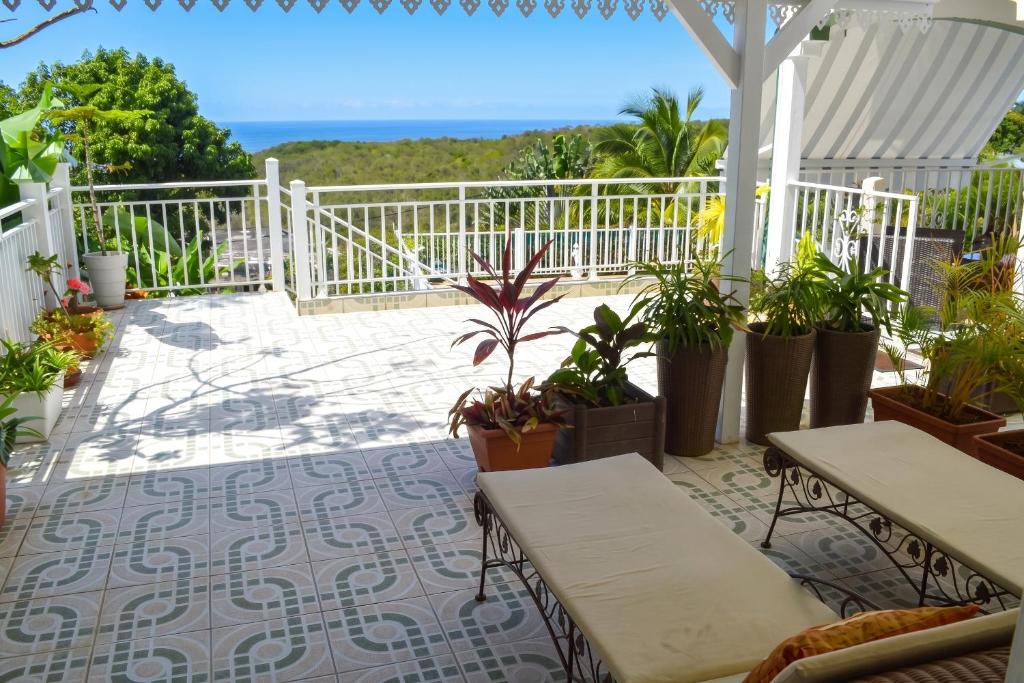 a patio with tables and potted plants and the ocean at "Studio charmant à Deshaies avec piscine partagée, 20 m²" in Deshaies