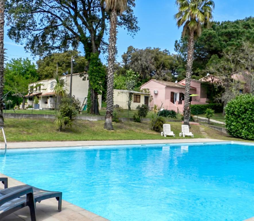 a swimming pool with palm trees and a house at Maison charmante à San-Nicolao avec piscine partagée in San-Nicolao