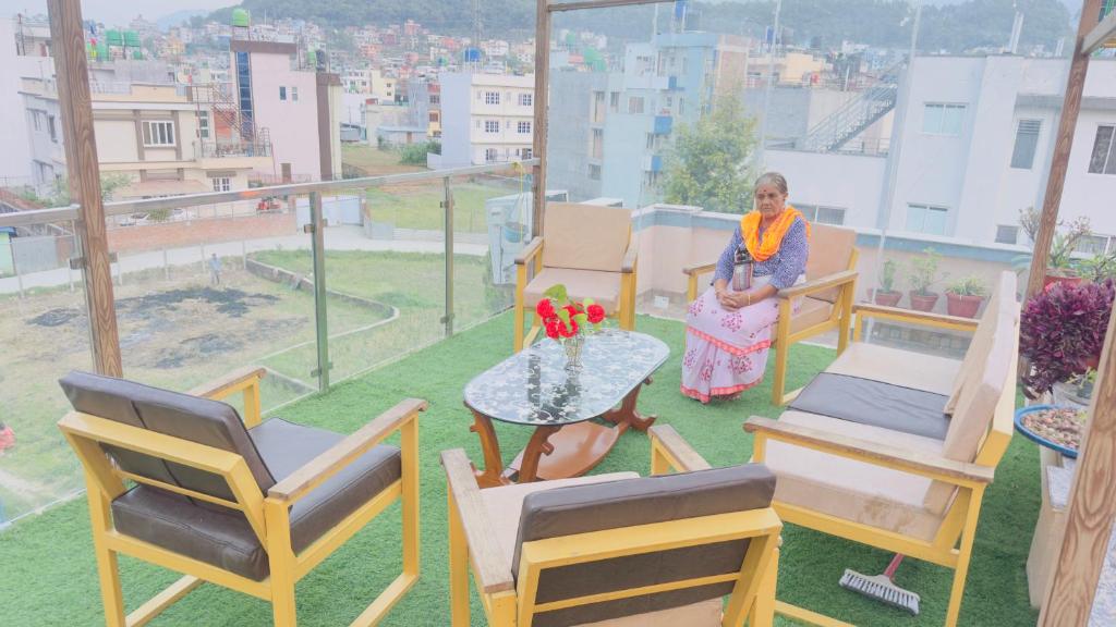 a woman sitting on a balcony with chairs and a table at Local feeling in Nepal in Bhaktapur