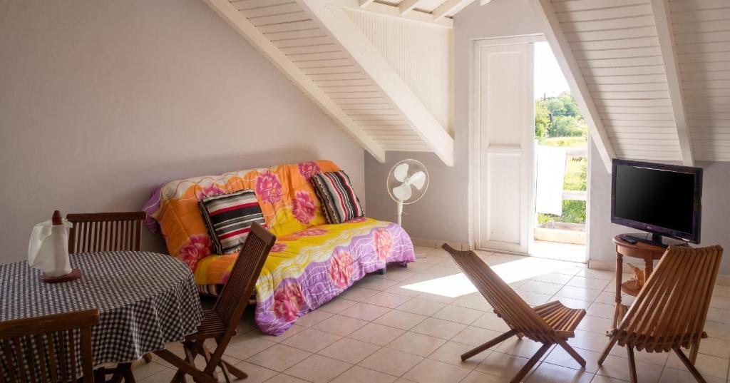 a room with a couch and a table and a tv at Appartement confortable à Capesterre, 40 m², jardin agréable in Rabi