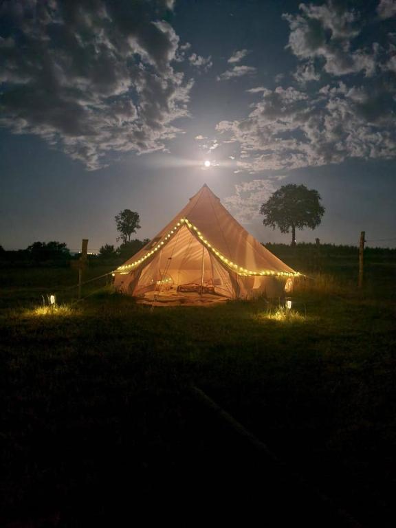 a tent with lights in a field at night at Le Nid des Prairies in La Chapelle-Engerbold