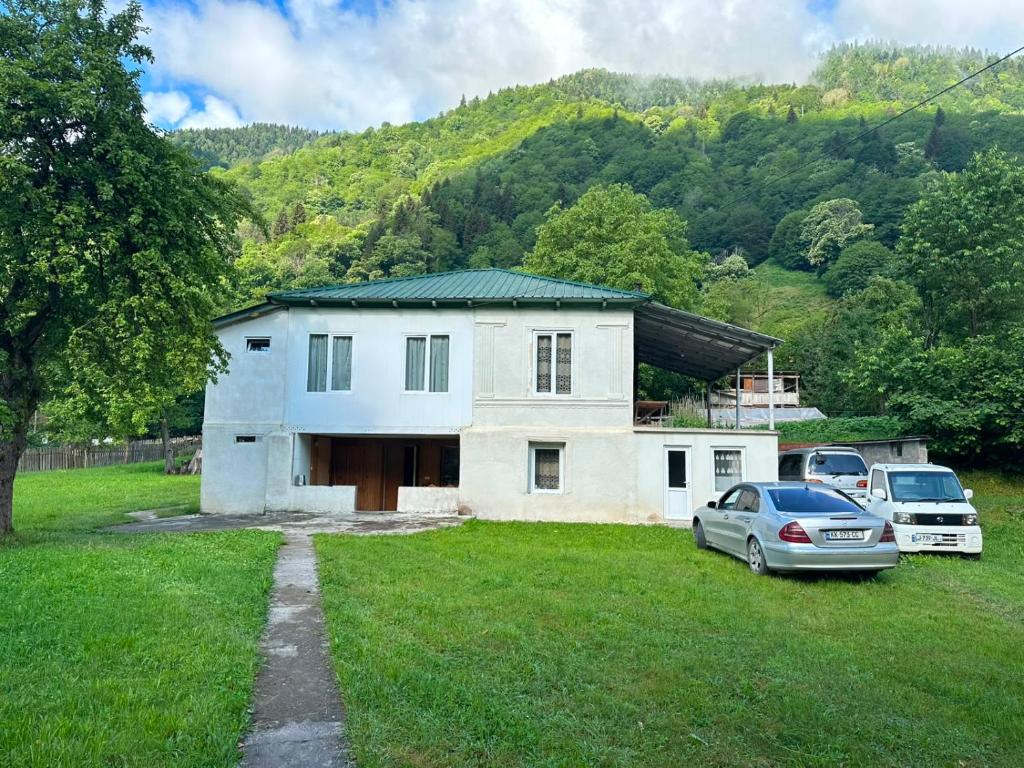 a white house with two cars parked in a yard at Guest House Babi in Letsperi