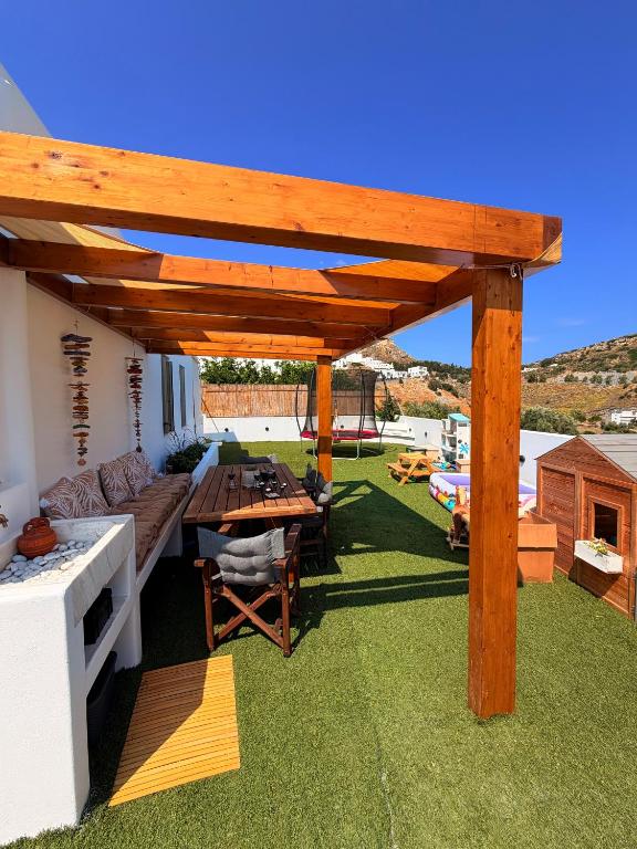 a patio with a wooden pergola on the grass at Apademia Comfort Studio 45 sqm in Skiros