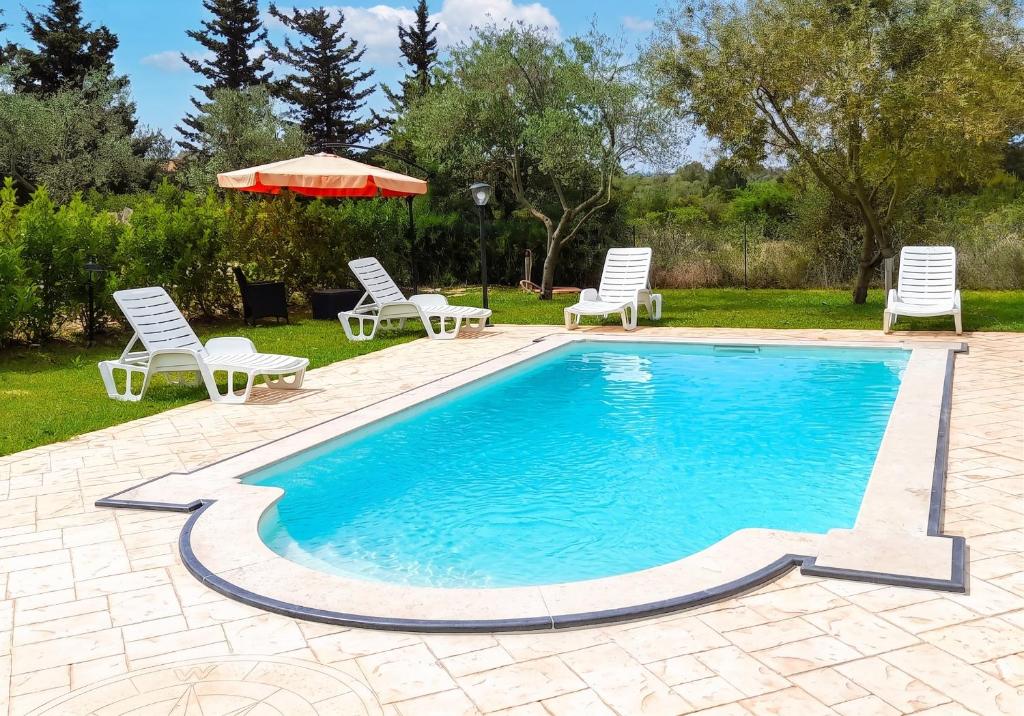 a swimming pool with two chairs and a umbrella at Charming Villa in Noto with Private Pool in Noto