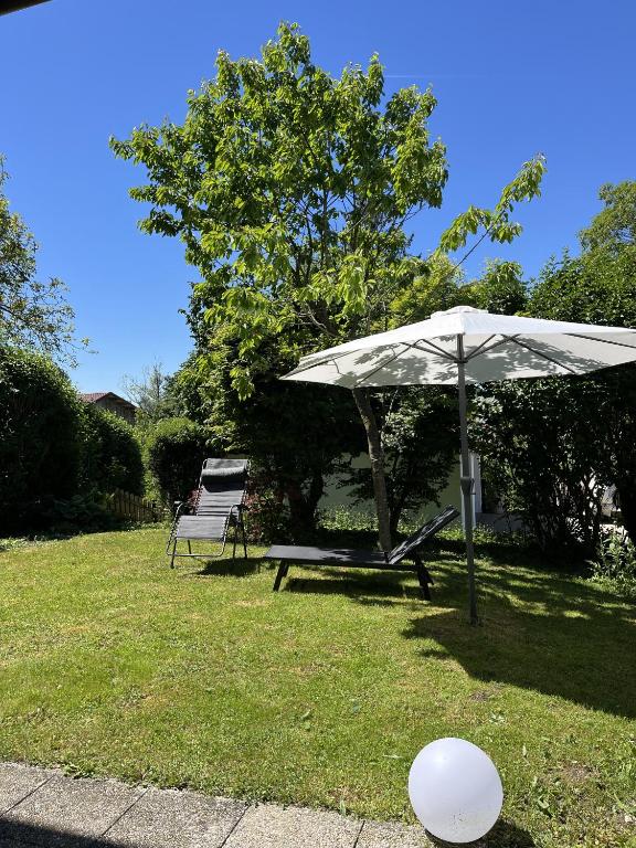 a white umbrella and a bench in a yard at Ferienwohnung Lisa in Grabenstätt