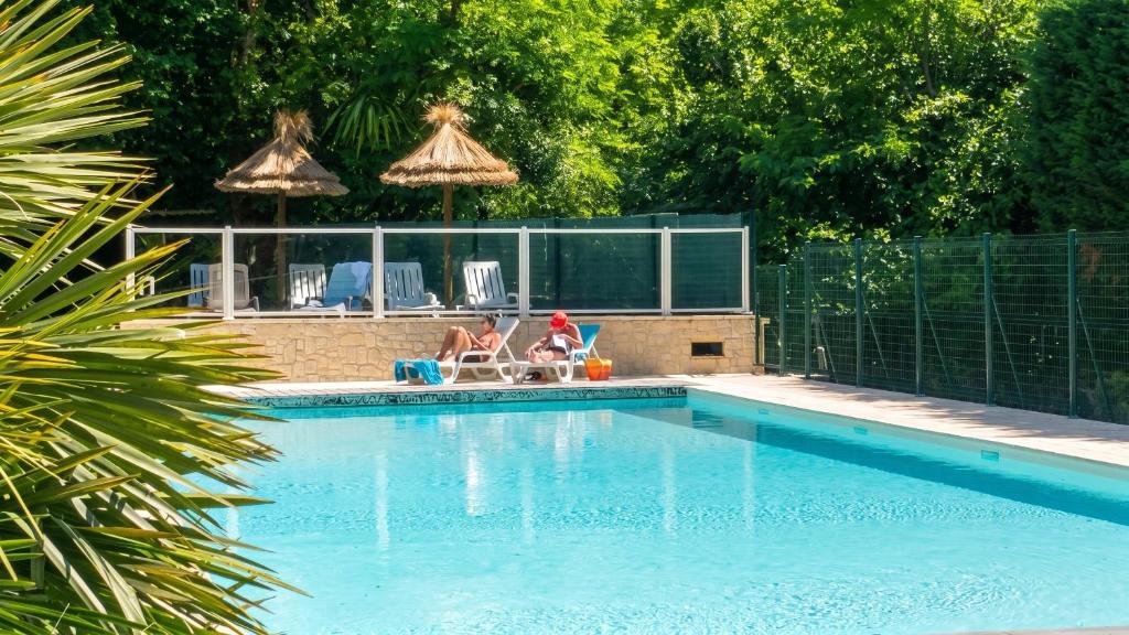 two people sitting in chairs near a swimming pool at Chalet charmant à Saint-Jean-du-Gard in Saint-Jean-du-Gard