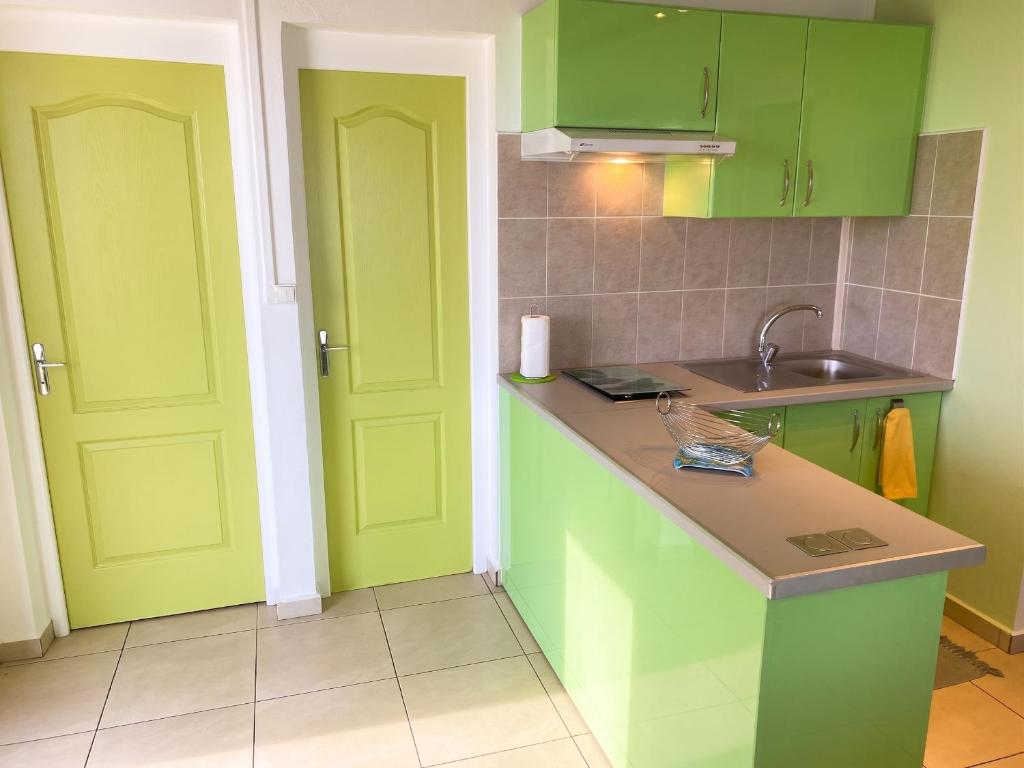 a kitchen with green cabinets and a sink at Appartement confortable avec vue sur mer à Bouillante, 50 m² in Bouillante