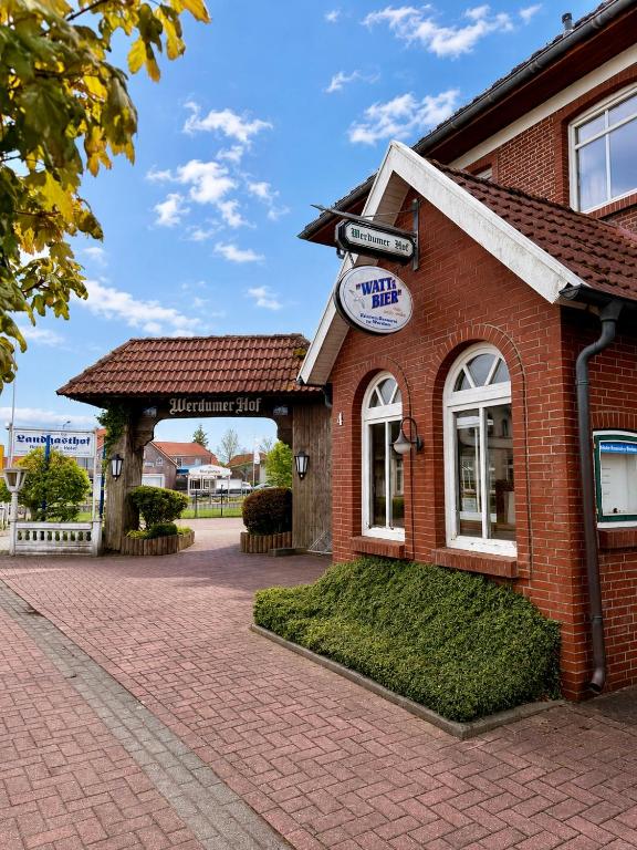 ein rotes Backsteingebäude mit einem Schild darauf in der Unterkunft Hotel Werdumer Hof in Werdum