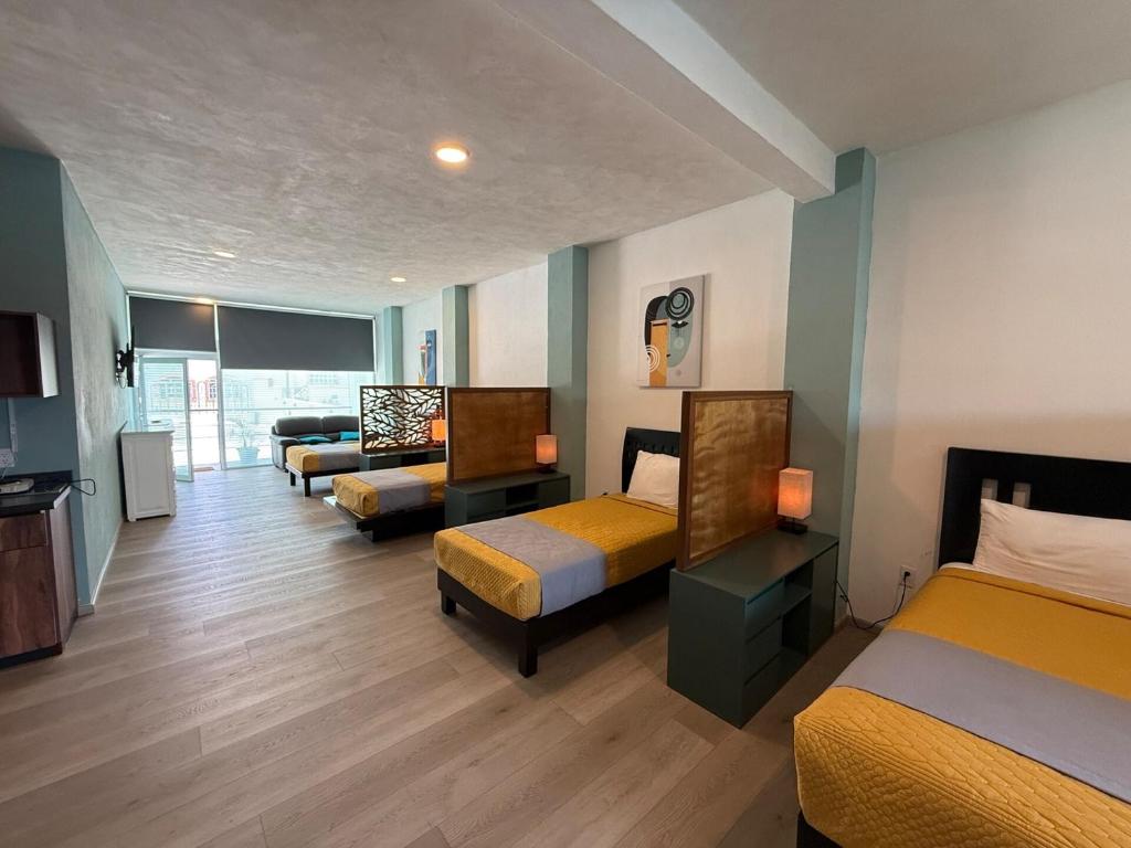 a hotel room with three beds and a couch at Apartment with Pool & Gym in Querétaro