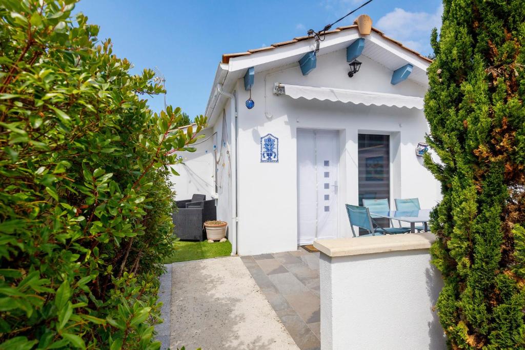 a white house with two chairs in a yard at Villa Sandra - Le Verdon, Medoc in Le Verdon-sur-Mer