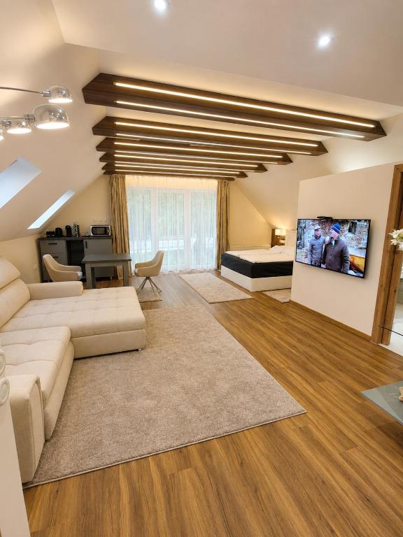 a large living room with a couch and a bed at Platán Panzió in Dobogoko