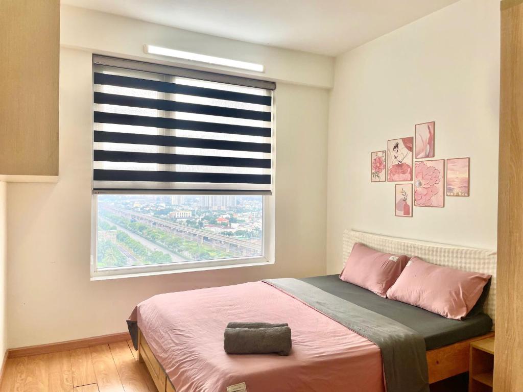 a bedroom with a bed and a window with a shutter at Saigon Getaway Apartment Thu Duc in Ho Chi Minh City