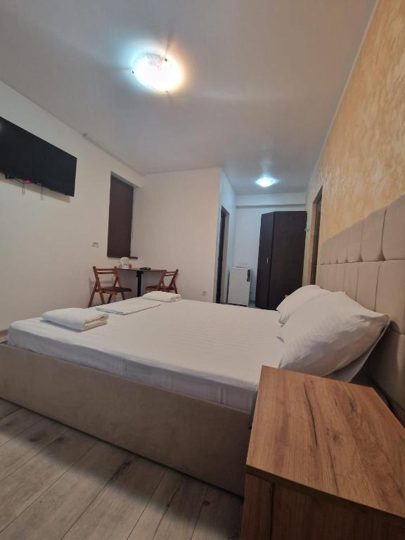 a bedroom with a large bed and a table at Harmony Rooms & Studios in Constanţa