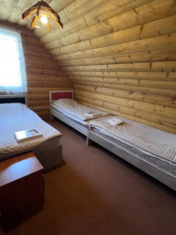 a bedroom with two beds in a wooden wall at Деревянный домик in Dolinka