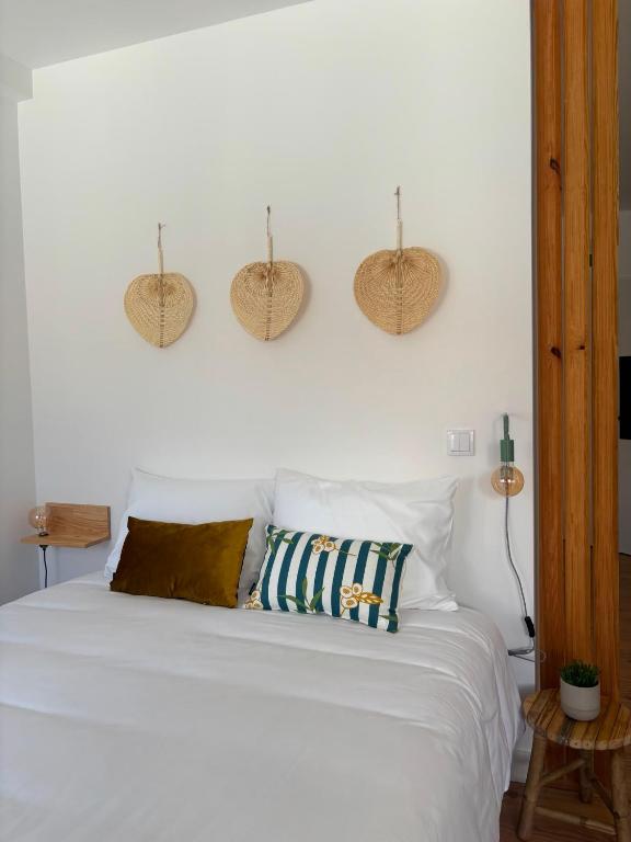 a bedroom with a white bed with baskets on the wall at Sobrado das Marias in Figueiró dos Vinhos