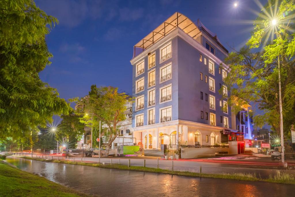a tall building next to a river at night at Tripli Hotels Blue Moon in Udaipur