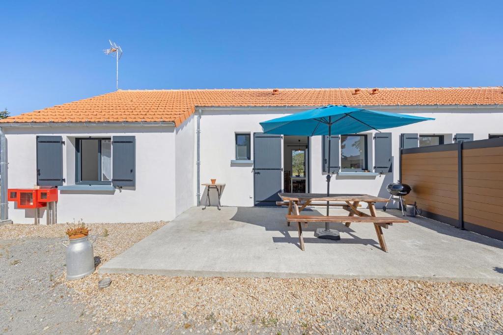 a picnic table with an umbrella in front of a house at La Maison Familiale in Commequiers