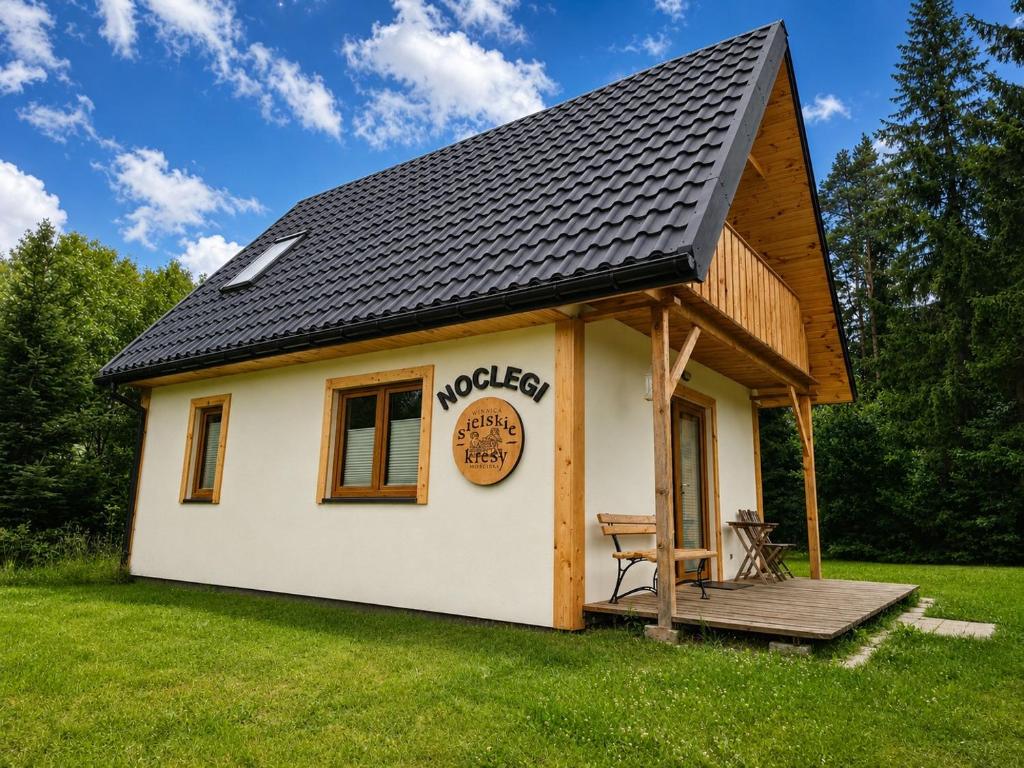 a tiny house with a porch and a deck at Winnica Sielskie Kresy in Michałowo