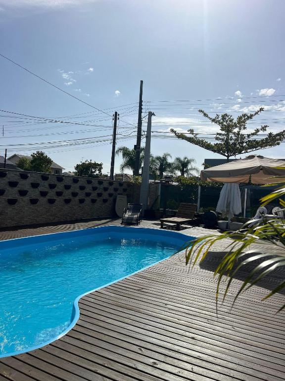 a swimming pool with a wooden deck and an umbrella at Pousada da Mel in Florianópolis