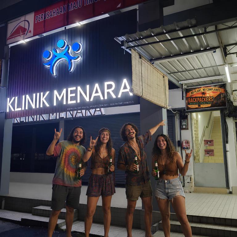 a group of people standing in front of a sign at No Plans No Complaints Backpackers Hostel in Ayer Itam