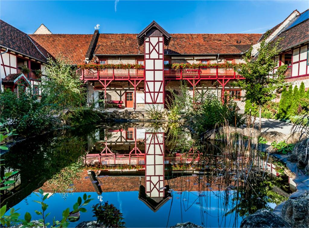 a building with a reflection in the water at Hotel Gut Voigtlaender in Blankenburg