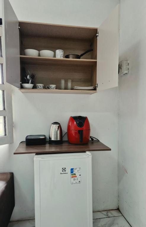 a small kitchen with a red appliance on a shelf at Suite 02 in Barcarena
