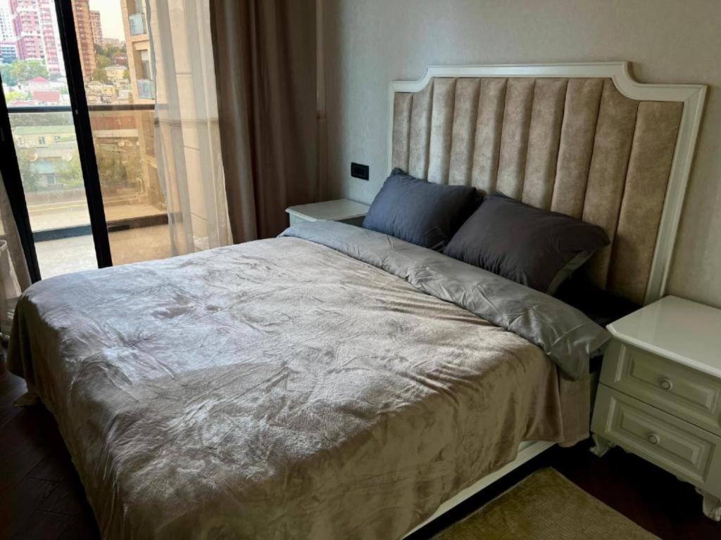a bedroom with a large bed and a window at Malibo Central Apartments in Baku