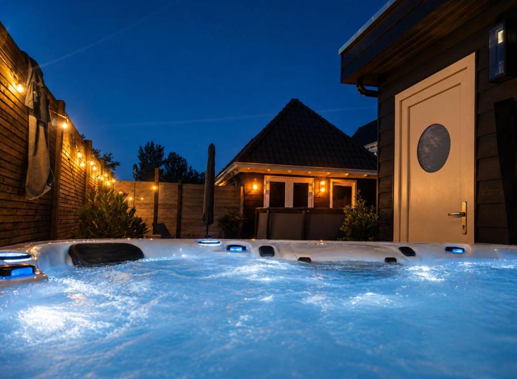 a hot tub in front of a house at night at Heidezee in Dishoek in Dishoek