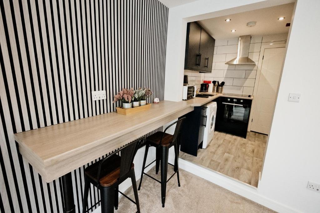 a kitchen with a wooden counter and stools at The Snug by JS Apartments in Blackburn