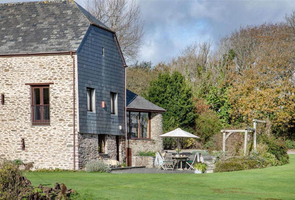 an old stone house with a table and an umbrella at Mowhay Barn in Torpoint