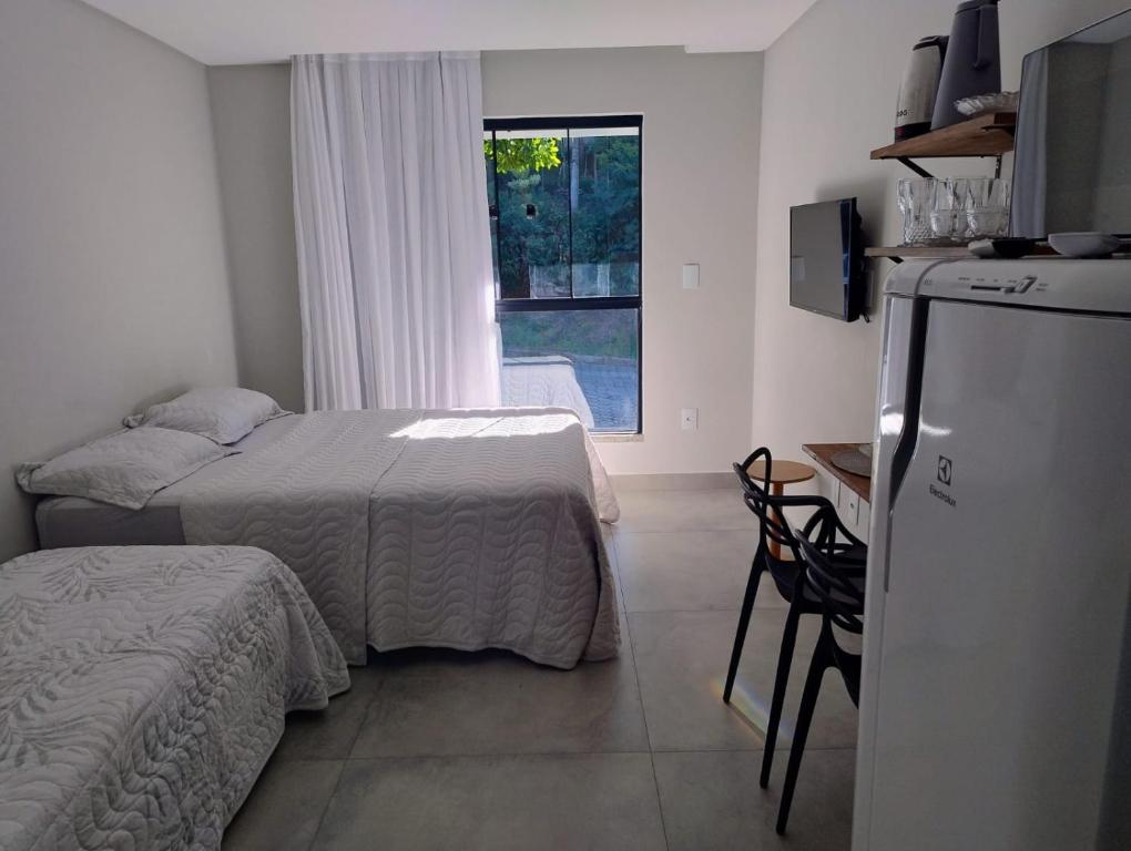 a bedroom with a bed and a refrigerator and a window at Villa Parati Bombinhas Sob Nova Direção in Bombinhas