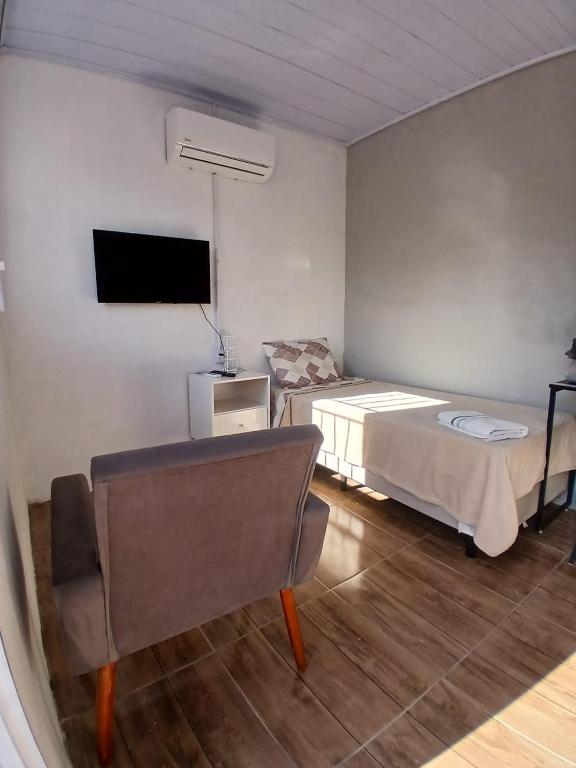 a bedroom with a bed and a tv and a chair at Hotel New in Alegrete