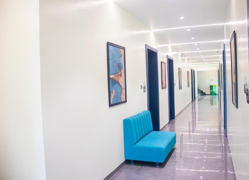 a hallway with a blue chair and paintings on the walls at Hotel Orbit in Parbhani
